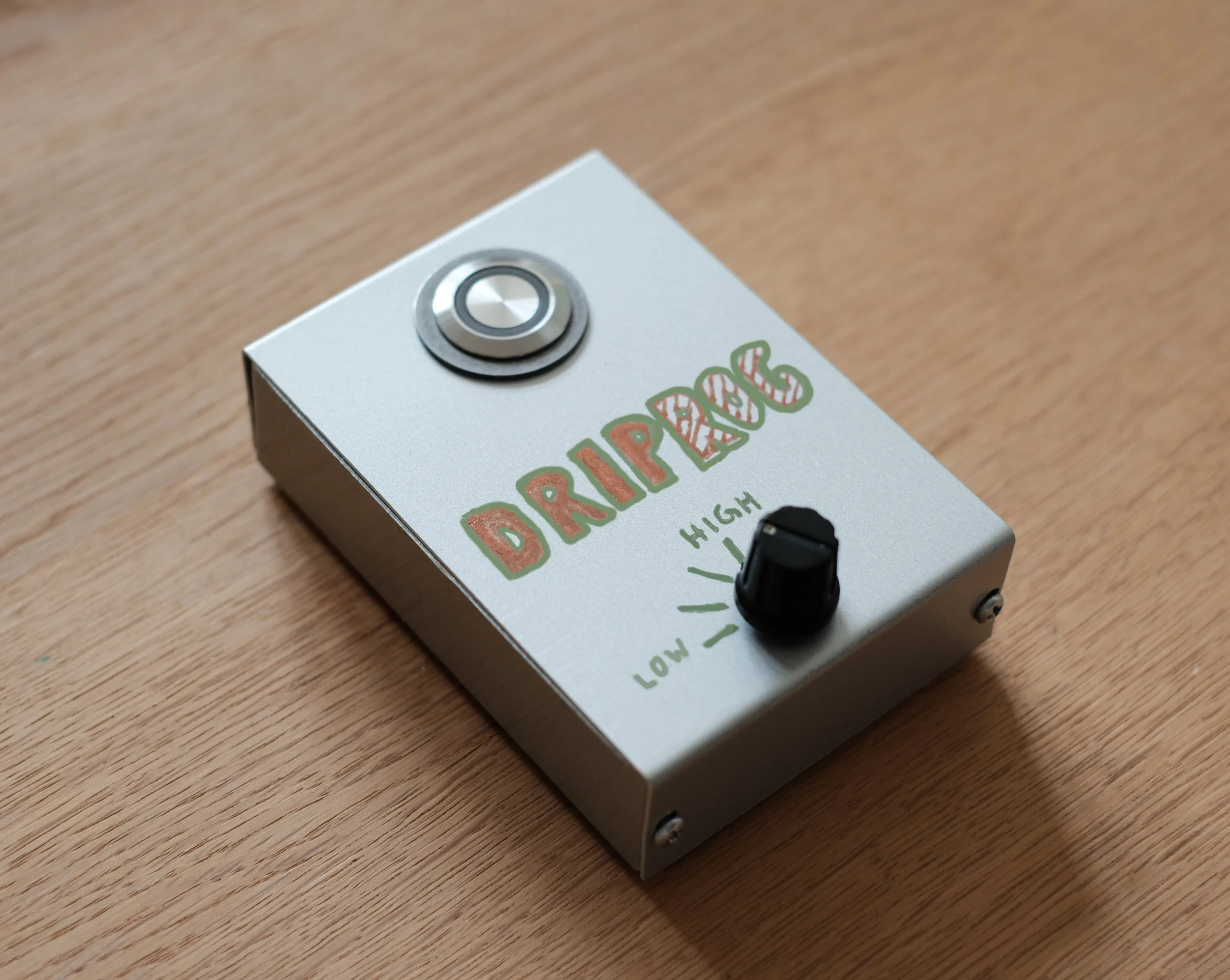 The DripRog field recorder: a small open enclosure on a wooden surface, with a single button, a gain selector and a status indicator.